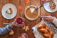 Cozy autumn table setting with pumpkin pie, bread, and drinks. Perfect for Thanksgiving vibes.